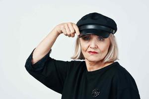 anziano donna nel un' nero cappello moda avvicinamento leggero sfondo foto