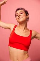 moda ritratto di un' donna con un' corto taglio di capelli di viola colore e un' Sorridi con denti nel un' rosso superiore su un' rosa sfondo felicità foto