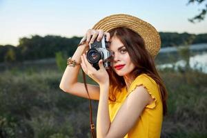 donna Tenere telecamera sembra in il telecamera lente rosso labbra cappello natura fresco aria stile di vita foto