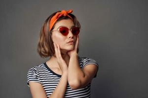 donna indossare occhiali da sole con arancia bendare su testa isolato sfondo moda foto