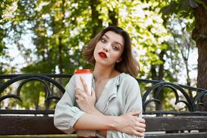 carino bionda seduta su un' parco panchina caffè estate tempo libero foto