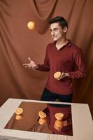 divertente uomo nel un' rosso camicia lanciare un arancia vicino il specchio foto