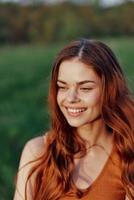 un' bellissimo dai capelli rossi donna ride e sorrisi con sua denti nel il luminosa tramonto luce del sole. il concetto di salutare vivente e bene nutrizione foto