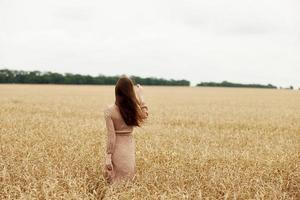 donna il contadino ha riguardato il maturazione di Grano orecchie nel presto estate soleggiato giorno foto