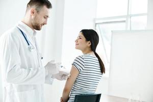 maschio medico nel un' bianca cappotto iniettare un' donna di mano nel un' Salute ospedale covid vaccinazione foto