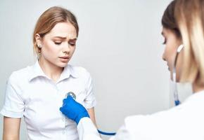 un' paziente si siede su un' sedia e un' donna medico con un' stetoscopio foto