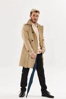 uomo nel beige cappotto ombrello nel mani Accessori moda autunno stile foto