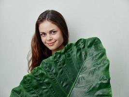 sorridente donna verde palma foglia attraente Guarda studio leggero sfondo foto