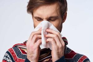 freddo uomo asciugandosi il suo naso con un' fazzoletto infezione virus leggero sfondo foto