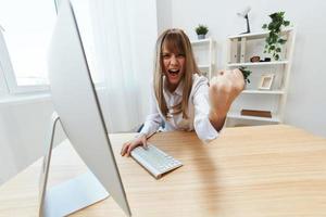 arrabbiato il male bionda donna d'affari urlando per subalterni tremante cazzotto a telecamera seduta a posto di lavoro nel moderno ufficio. irritata direttore opera su computer in linea nel finanziario società. largo angolo foto