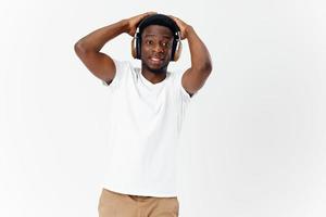 uomo di africano aspetto nel bianca maglietta indossare cuffie musica foto