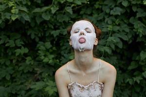 ritratto di un' ragazza anti età maschera lingua su emozione modello cosmetologia cespugli nel il sfondo foto