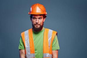 uomo nel costruzione uniforme arancia casco sicurezza emozioni blu sfondo foto