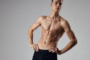 sportivo uomo Tenere mani su cintura su grigio sfondo ritagliata Visualizza modello foto