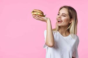 carino bionda nel bianca maglietta Hamburger delizioso cibo ristorante foto