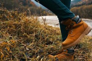 Da donna piedi jeans scarpe asciutto erba autunno fiume montagne nel il distanza foto