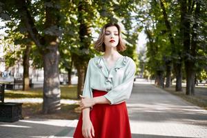 bella donna nel rosso gonna nel il parco camminare stile di vita fresco aria foto