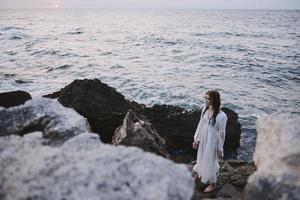 donna viaggiatore nel bianca vestito a il mare spiaggia la libertà foto