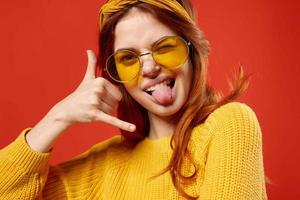 donna nel giallo bicchieri con un' bendare su sua testa giallo maglione fricchettone rosso sfondo foto