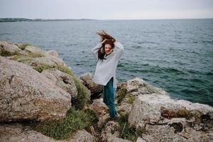 bella donna nel un' grigio maglione sta su un' roccioso riva natura inalterato foto