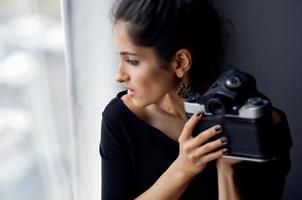 bella donna Tenere un' telecamera vicino il finestra decorazione moda stile di vita studio foto