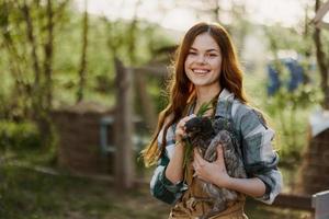donna Tenere un' giovane, salutare pollo e sorridente nel natura su un' azienda agricola in crescita organico, salutare cibo foto