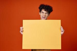 emotivo uomo con Riccio capelli giallo manifesto nel mani foto