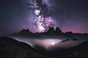 latteo modo al di sopra di montagne nel nebbia a notte nel estate. paesaggio con nebbioso alpino montagna valle foto