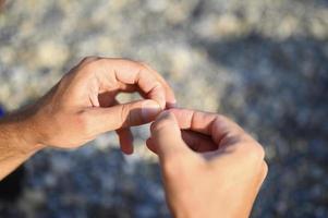 mani dell'uomo che lega una lenza su un amo da pesca foto