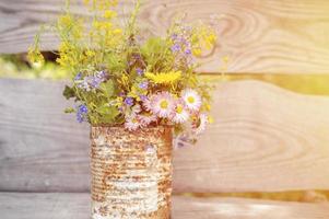 un bouquet di fiori di campo di nontiscordardime, margherite e denti di leone gialli in piena fioritura in un vaso rustico foto