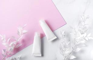 tubetti bianchi di crema su fondo in marmo e rosa foto