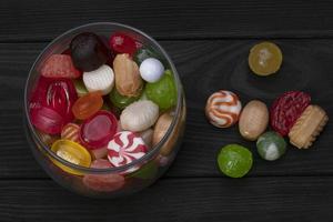 caramelle nel un' vaso su un' buio sfondo. multicolore caramello su un' di legno tavola. dolci. foto