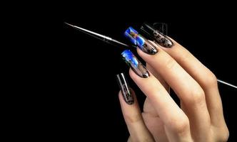 mano con un' bellissimo manicure e un' spazzola su un' nero sfondo. chiodo design. esteso chiodo. foto