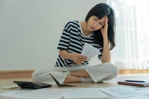 stressato e mal di testa asiatico donna con grande fatture o fatture no i soldi per pagare per spese e credito carta debito. carenza, finanziario i problemi, mutuo, prestito, fallimento, fallito, povero, vuoto portafoglio foto