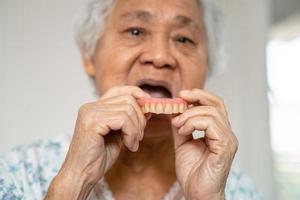 asiatico anziano donna paziente Tenere per uso dentiera, salutare forte medico concetto. foto