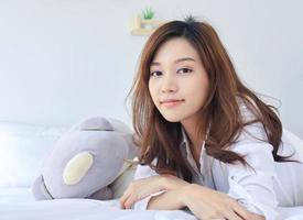 bella donna asiatica sorridente a letto in vacanza foto