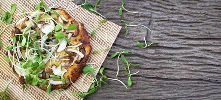 pizza vegetariana fatta in casa con germogli di girasole su uno sfondo di tavolo in legno foto