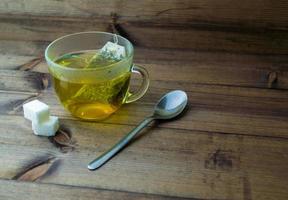 verde tè nel un' bicchiere tazza, zucchero e un' cucchiaio. foto