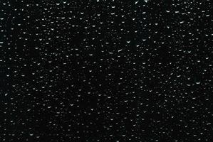 gocce di pioggia su nero finestra bicchiere come sfondo foto