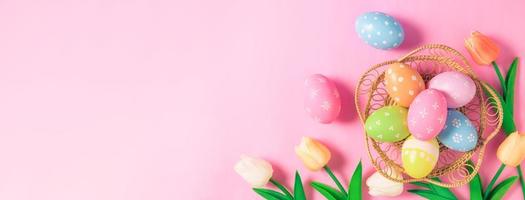 contento Pasqua vacanza saluto carta concetto. colorato Pasqua uova e primavera fiori su pastello rosa sfondo. piatto posizione, superiore Visualizza, copia spazio. foto