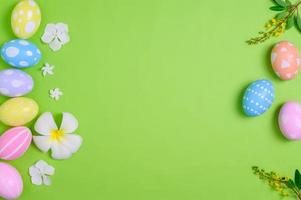contento Pasqua vacanza saluto carta design concetto. colorato Pasqua uova e primavera fiori su pastello verde sfondo. piatto posizione, superiore Visualizza, copia spazio. foto