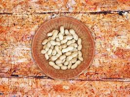 arachidi intere in una ciotola di vimini su uno sfondo di tavolo in legno