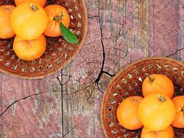 arance in una ciotola di vimini su uno sfondo di tavolo in legno foto