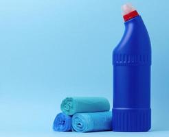 spazzatura borse e un' blu bottiglia con detergente su un' blu sfondo foto