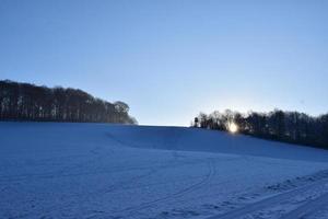 neve coperto collina con Basso sole foto