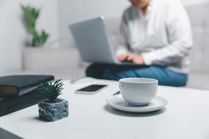 sociale media giorno concetto. femmina libero professionista di partenza Lavorando giorno presto nel mattina potabile caffè nel vivente camera per sito web con utilizzando moderno il computer portatile computer. donna d'affari Lavorando nel casa ufficio. foto