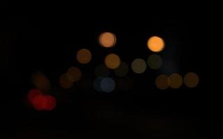 sfocato, bokeh di luci per auto nella notte oscura della città foto