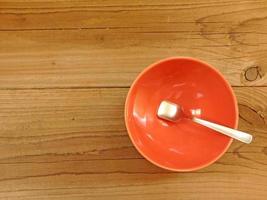 cucchiaio di metallo in una ciotola rossa su uno sfondo di tavolo in legno foto