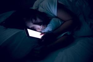 asiatico donna giocando gioco su smartphone nel il letto a notte, Tailandia persone, tossicodipendenti sociale media foto