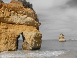 una grande roccia sulla spiaggia di sabbia foto